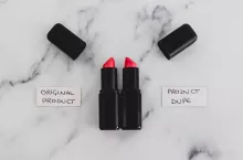 beauty industry competition conceptual still-life, two identhical looking lipsticks with Original Product and Product Dupe labels