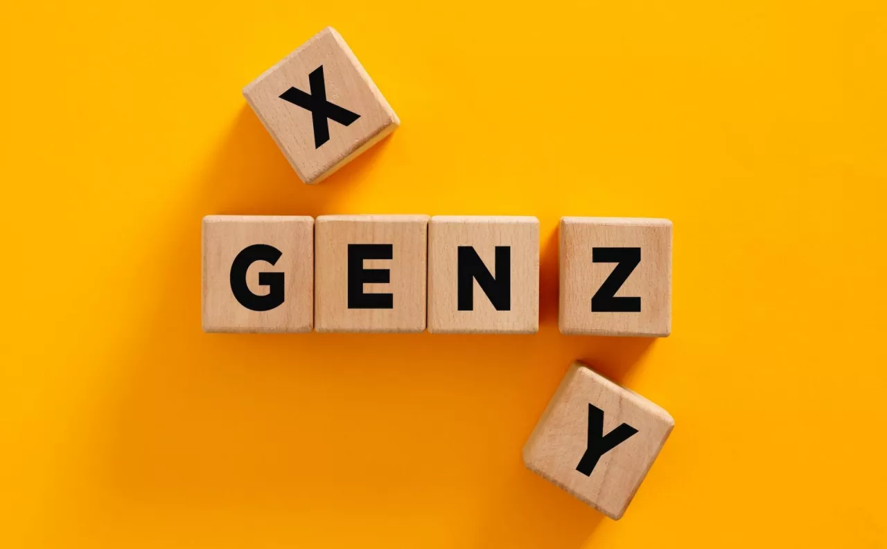 Wooden cubes composing the acronym gen z with other two cubes, representing the generation x and generation y on yellow background. Generation gap or generation chance concept.